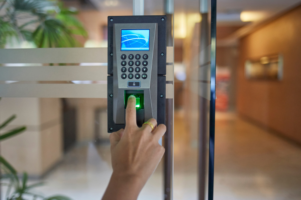 Biometric fingerprint scanner for office security, showing a person's finger being scanned on an electronic door access control system.
